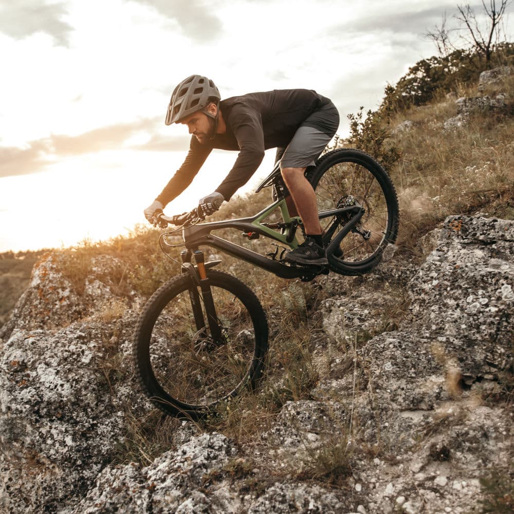 Man riding bike on rocky slope at sunset