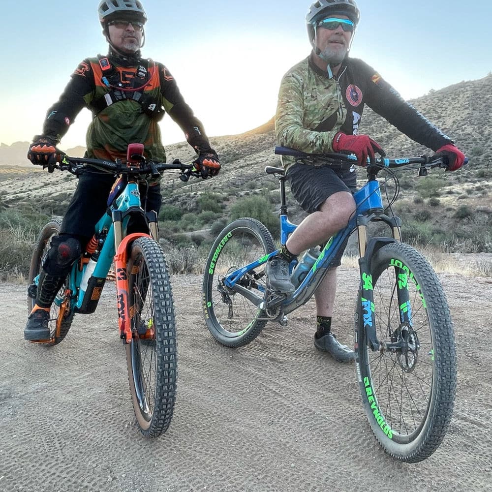 two mountain bikers resting on top of a mountain